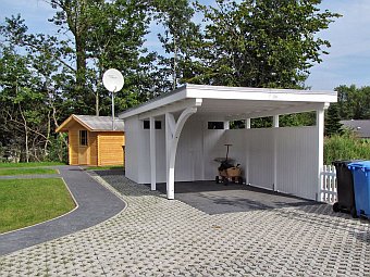 Der Carport und dahinter das Gartenhaus mit integrierter Sauna