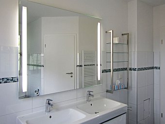 Bad im Erdgeschoss mit bo­den­glei­cher Dusche, Doppelwaschbecken und WC