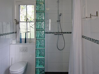 Bad im Erdgeschoss mit bo­den­glei­cher Dusche, Doppelwaschbecken und WC